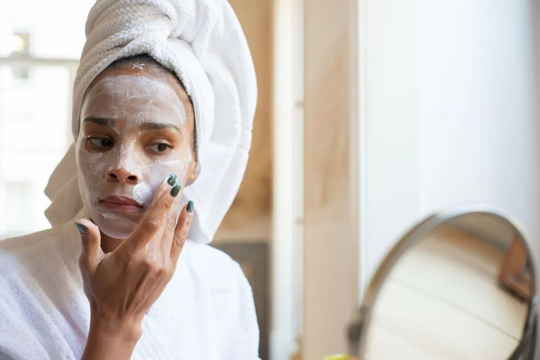 Een vrouw met een verzorgend masker en een handdoek om het haar